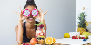 woman smiling holding fruit over her eyes